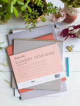 The Sunday Sessions - Planning My Week notebook by Write To Me is sitting on a table next to a plant, aiding in productivity and organization.