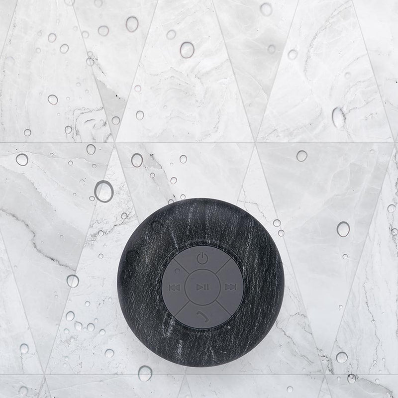 An Albi wireless shower speaker - Assorted Natural Prints is sitting on top of a marble wall.