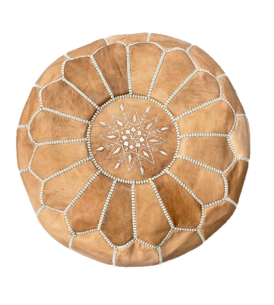 A Moroccan Leather Pouf - Tan, also known as an ottoman or footstool, adorned with stylish beading, by Flux Home.