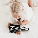 A little girl laying on a bed reading a My Numbers | Luxe Soft Cover Book by My Family Book.