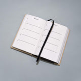 An open Canvas One Line a Day notebook with a black ribbon on it.