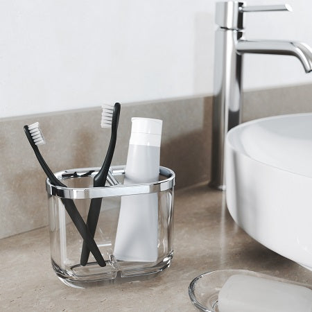 This bathroom sink features two toothbrushes neatly placed in a sleek Junip Toothbrush Holder - Chrome / Clear from the Umbra Junip collection.