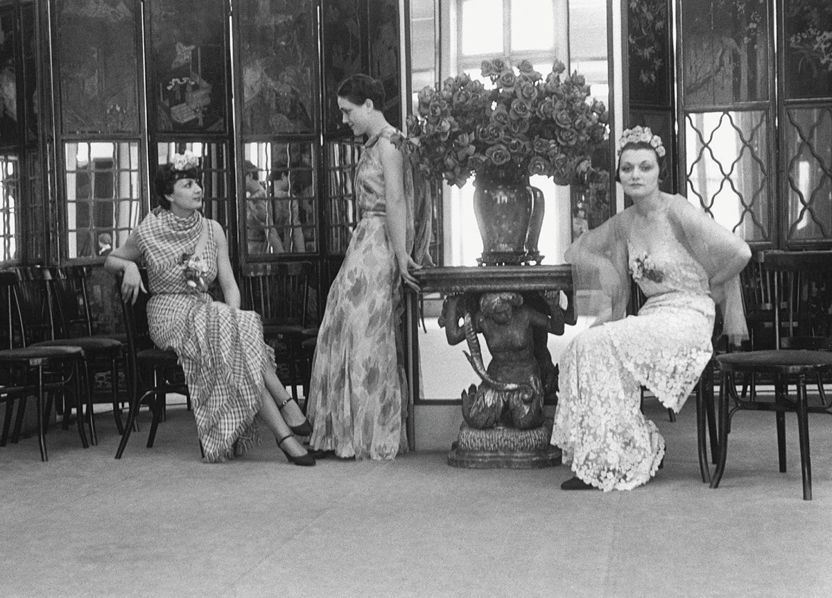 Black and white photo of three women in Chanel gowns seated in an elegant room