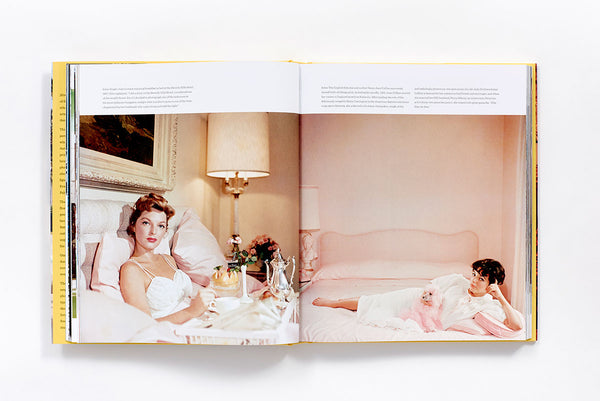 An open Slim Aarons: Women book with two women on a bed.