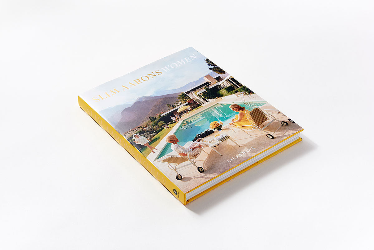 A Slim Aarons: Women book on a white surface with a picture of a pool.