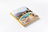 A Slim Aarons: Women book on a white surface with a picture of a pool.