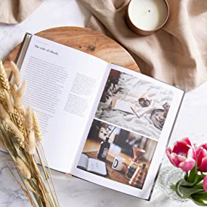 The New Mindful Home: And How to Make it Yours collection from Books, adorned with flowers and a candle, creating a mindful home interior design.
