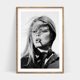 A black and white photo of a woman smoking a cigarette, available in BARDOT Art Prints.