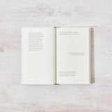 An open book on a wooden table showcasing All That You Deserve | Jacqueline Whitney design books by Thought Catalog.