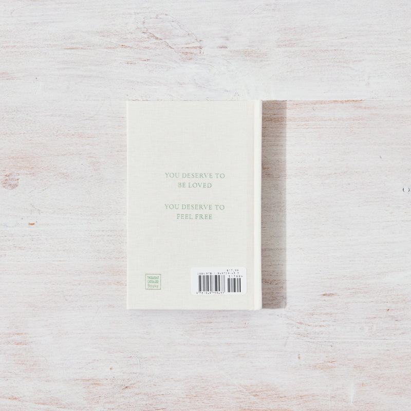 A white notebook on a wooden surface, perfect for All That You Deserve | Jacqueline Whitney design books from Thought Catalog.