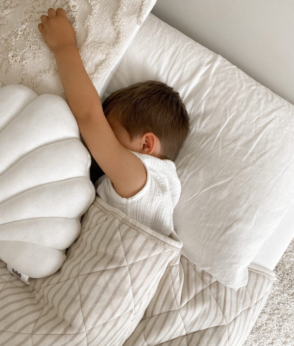 A young boy sleeping on a pure cotton pillow with a LARGE SHELL CUSHION - IVORY from Bengali Collections.