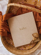 A nursery diary basket containing a baby's first five years book, placed on a bed by Write To Me.