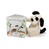 A cheeky black and white Jellycat puppy with a Puppy Makes Mischief board book and a stuffed toy.