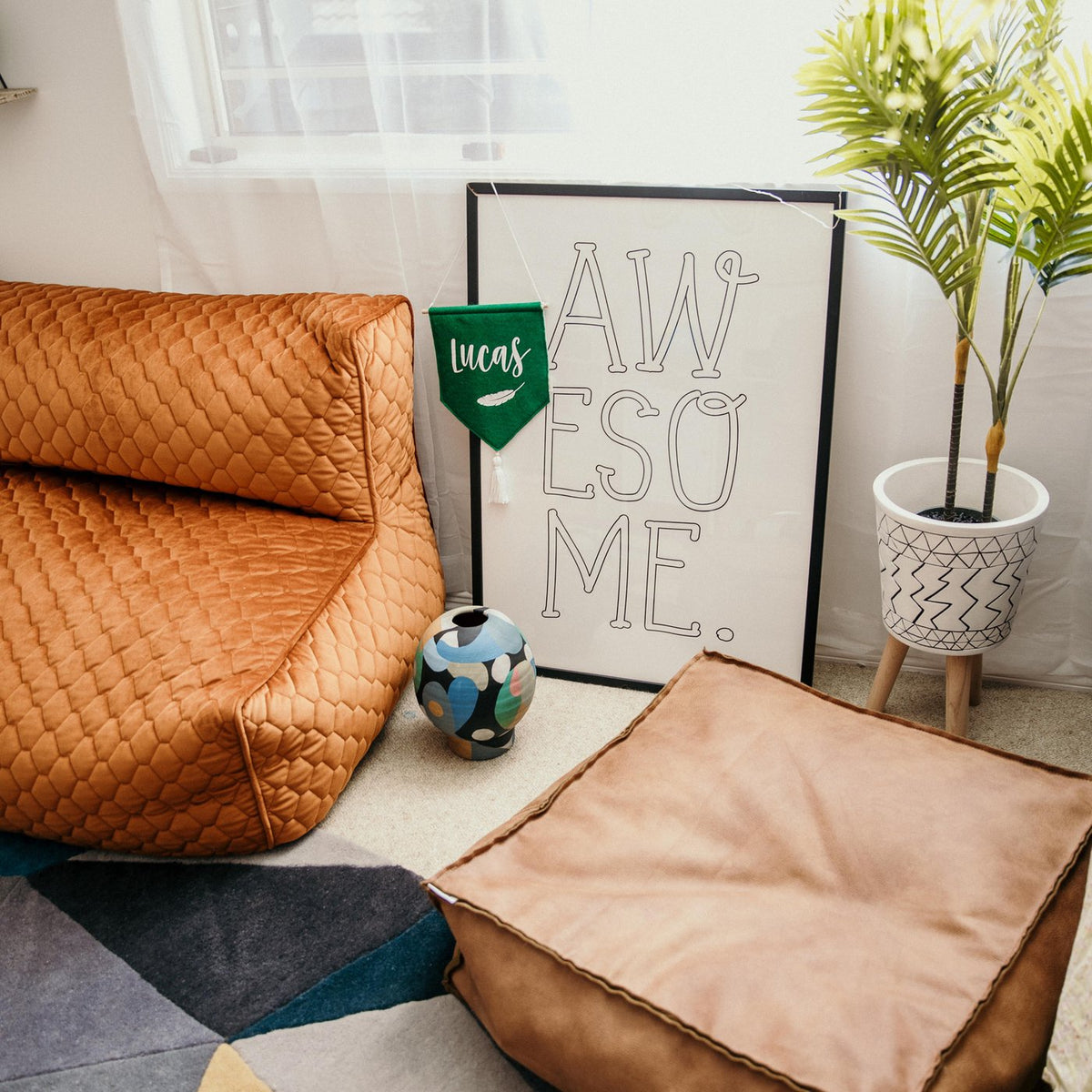 Awesome print in a black frame behind tan leather beanbags and a plant