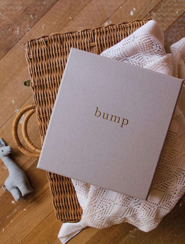 A BUMP | MY PREGNANCY JOURNAL | LIGHT GREY wicker basket on a wooden floor with a "bump" sticker on it. Brand Name: Write To Me