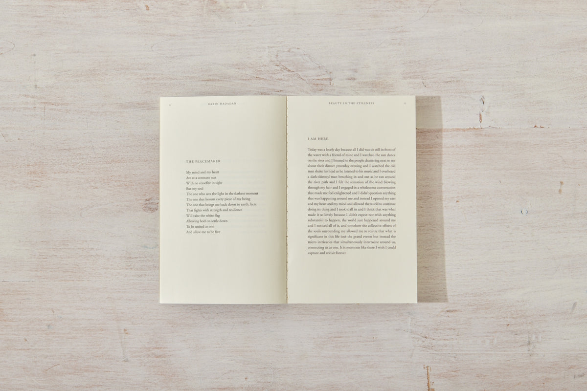 An open book, "Beauty in the Stillness," on a wooden surface by Thought Catalog.