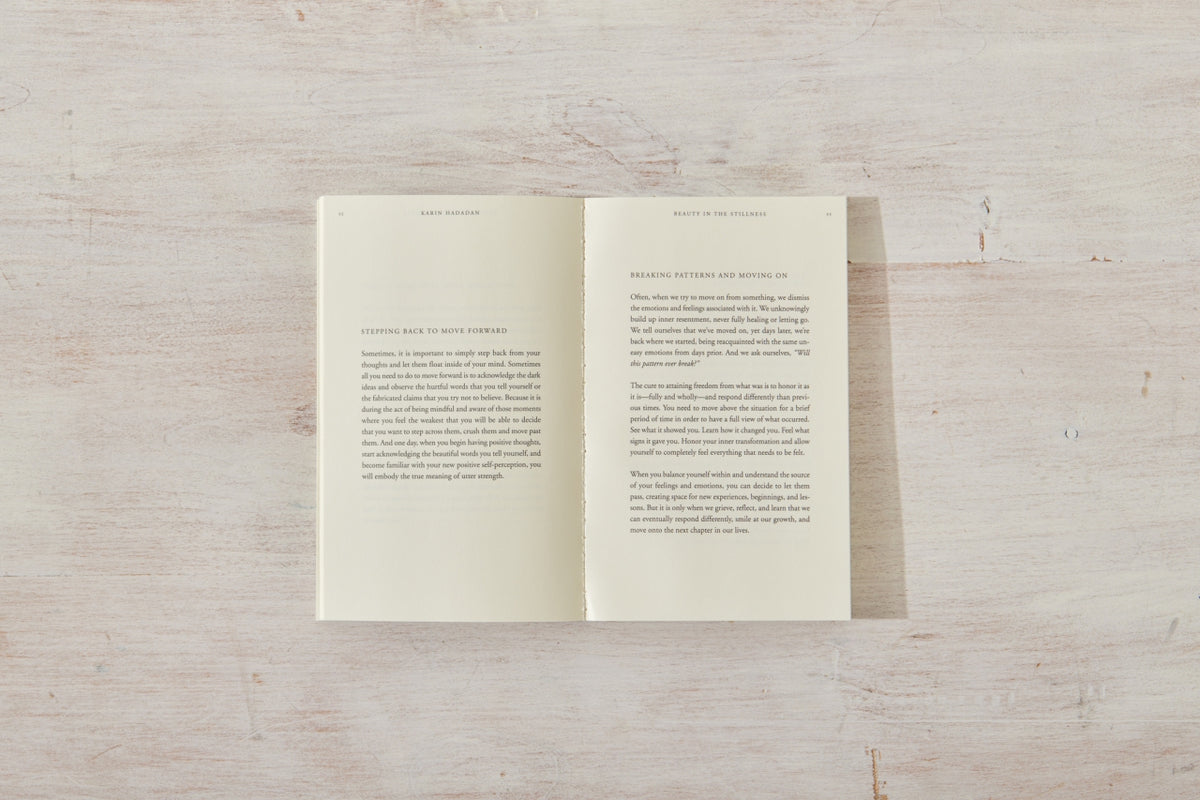An open Beauty in the Stillness book on a wooden surface.