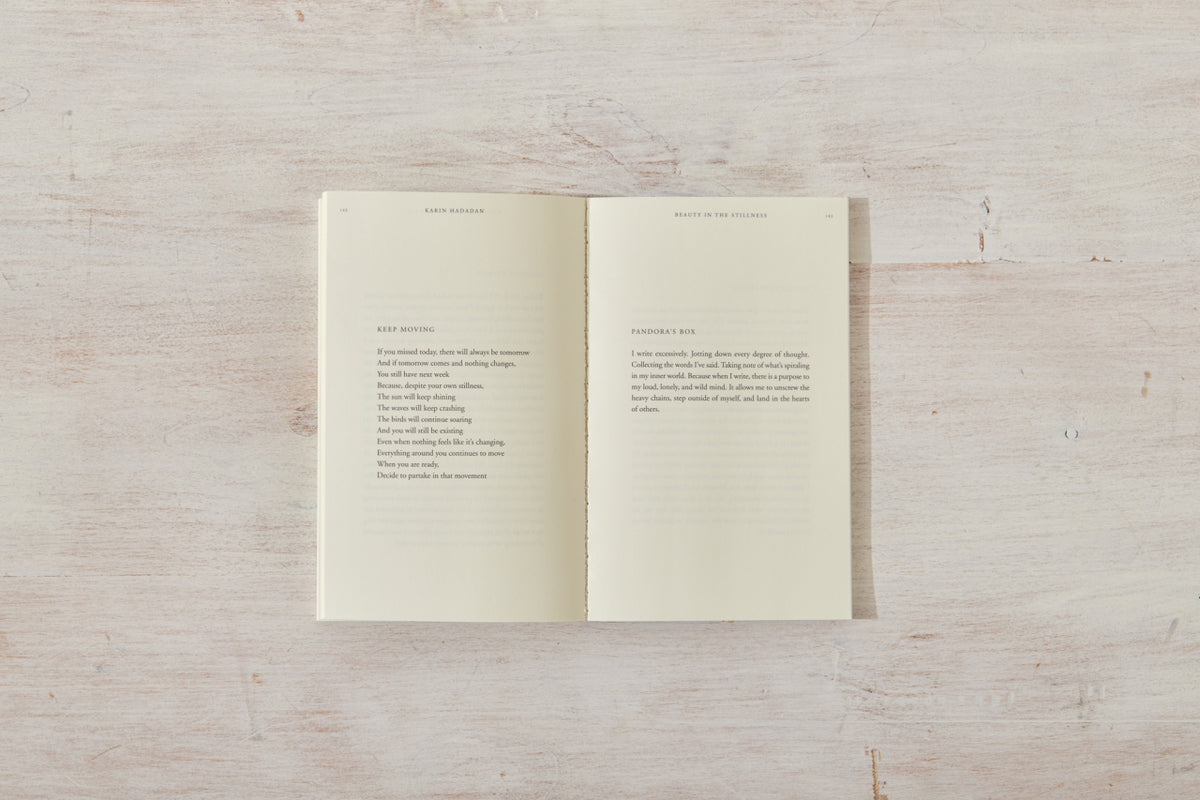 A "Beauty in the Stillness" book with an open page on a wooden surface.