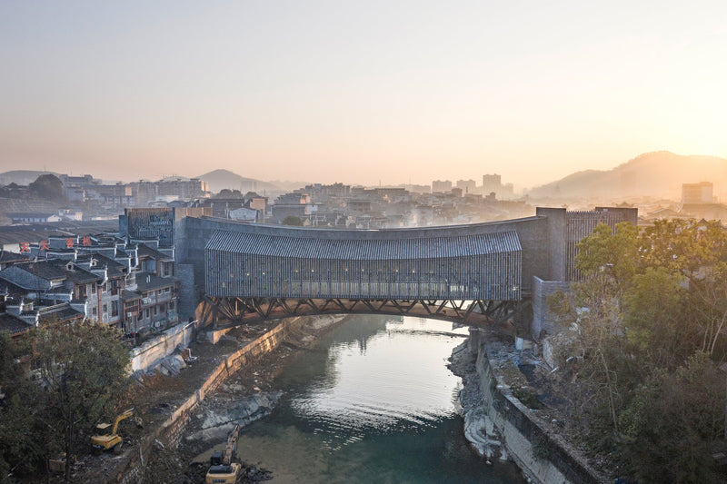 A stunning bridge spanning a serene river in an urban landscape, showcasing exquisite architectural design influenced by BEAUTY AND THE EAST brand.