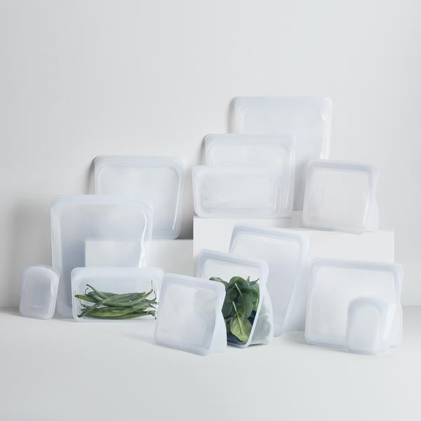 A group of white Stasher bags with vegetables in them.