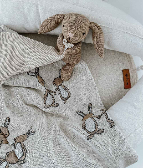 A BUNNY BLANKET from Bengali Collections is laying on a bed with a teddy bear.