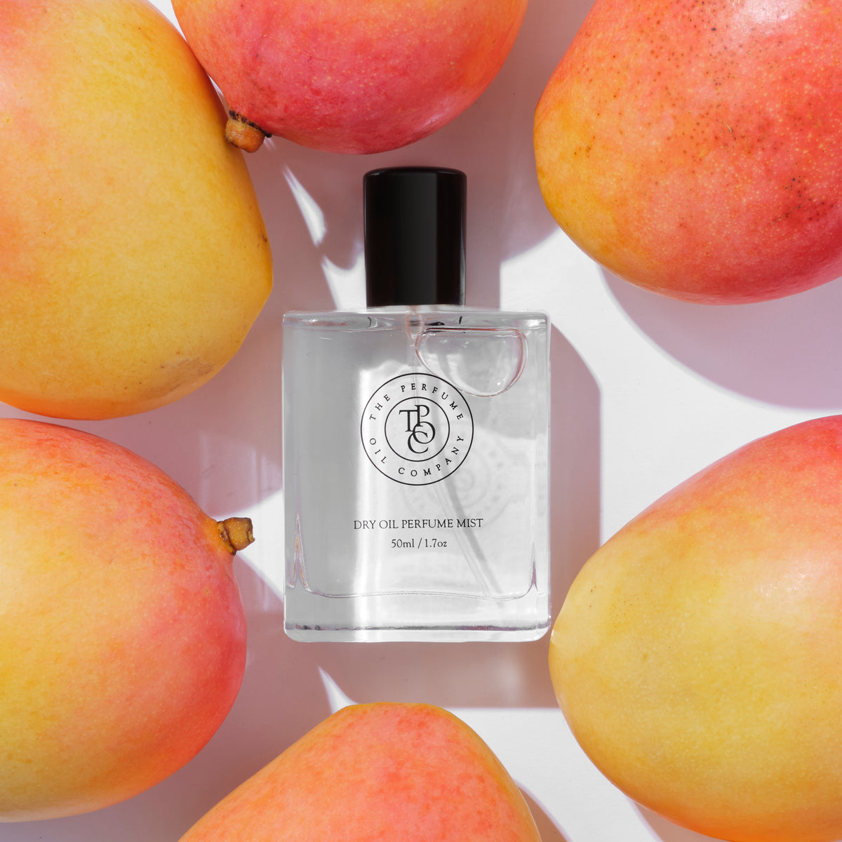 Perfume bottle surrounded by ripe mangoes