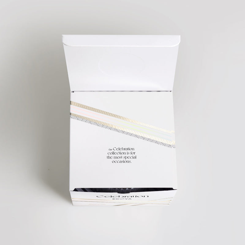 A white box with a gold label on it containing an Ecoya Celebration | White Musk & Warm Vanilla Grand Candle.