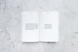 An open book on a concrete surface with Ceremony | Brianna Wiest design books by Thought Catalog.