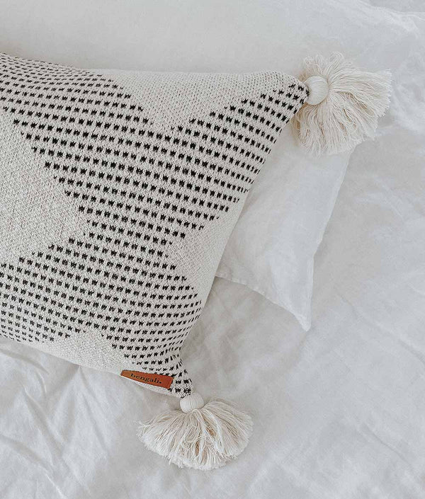 A white and black pillow with COAST CUSHION COVER from Bengali Collections.
