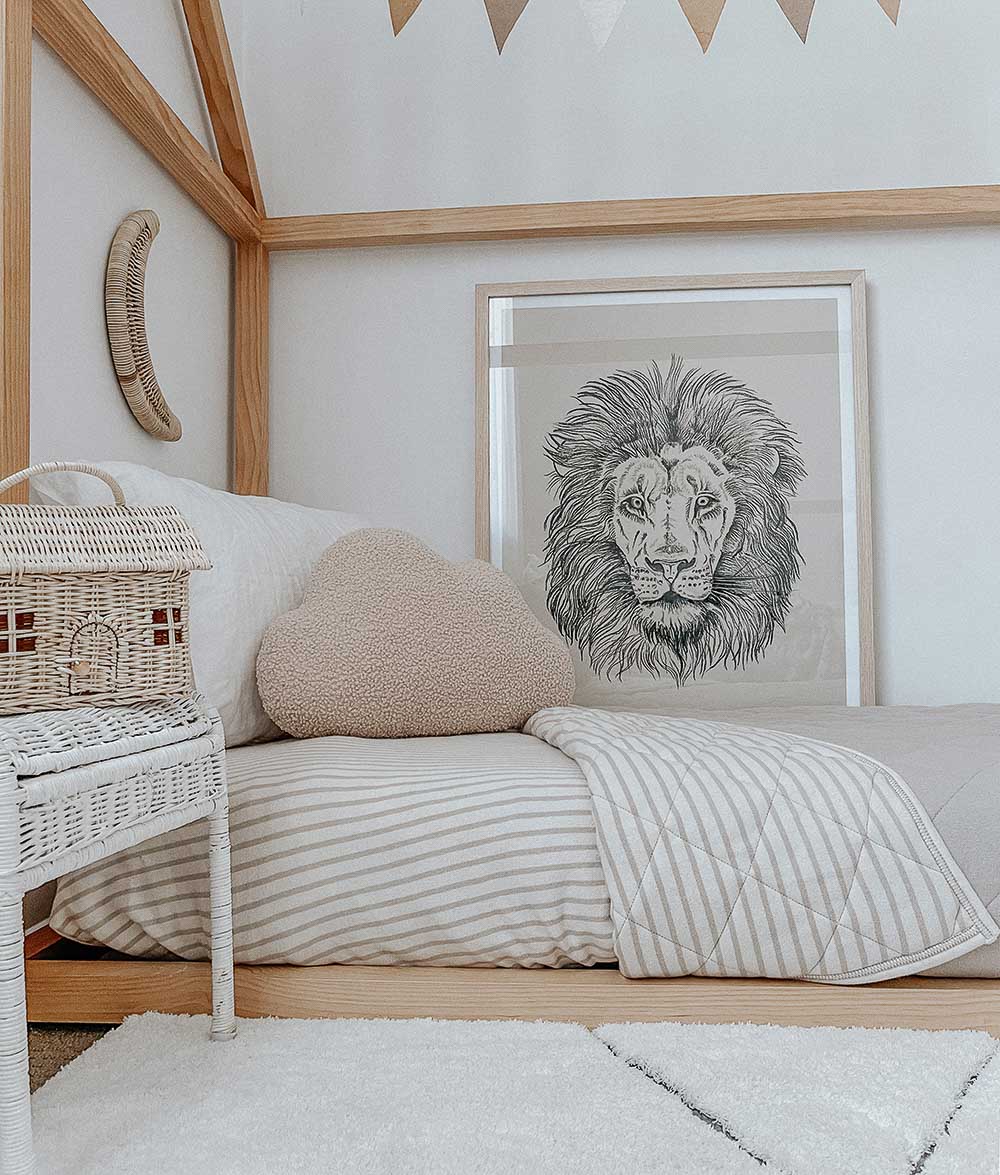 Timber house bed with a greige pinstripe fitted sheet, pinstripe quilt and a lion print on the wall