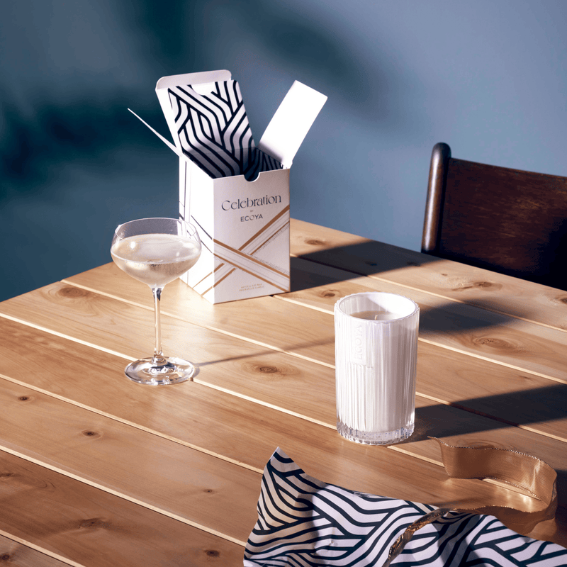 A scandinavian-inspired fragrance, the White Musk & Warm Vanilla Candle by Ecoya creates a cozy ambiance on a wooden table.