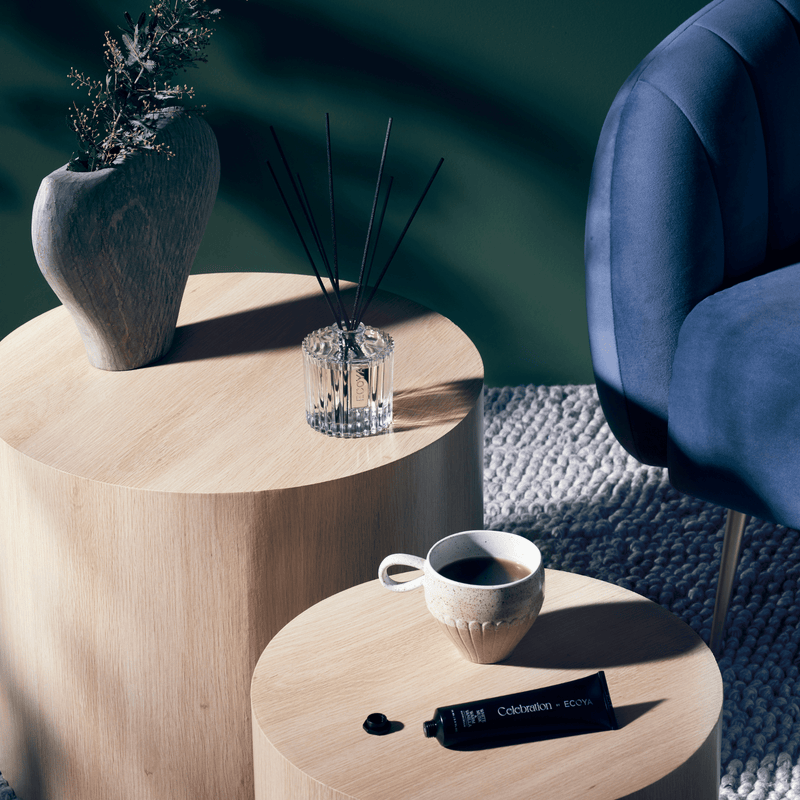 Two wooden tables adorned with a fragranced diffuser and accompanied by Ecoya Celebration | White Musk & Warm Vanilla, perfect for home design enthusiasts or as thoughtful gifts.