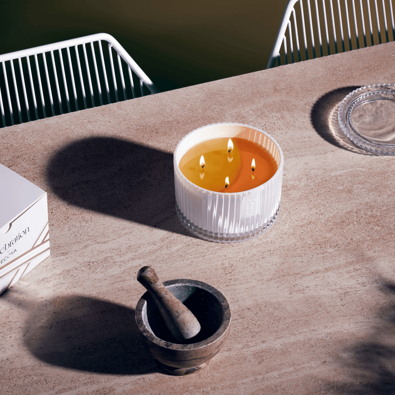 A Celebration | White Musk & Warm Vanilla Grand Candle scented with White Musk & Warm Vanilla from Ecoya sits on a table next to a mortar and pestle.
