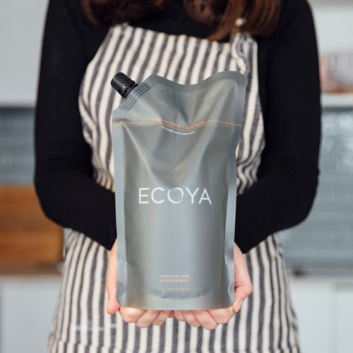 A woman showcasing the Ecoya Kitchen | Fragranced Dish Liquid Refill, a perfect gift for those who appreciate Scandinavian and home design.