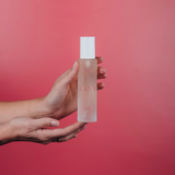 A person showcasing the design of an Ecoya Fragranced Room Spray on a pink background.