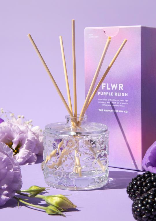The Aromatherapy Co's FLWR Diffuser - Purple Reign on a purple background with blackberries and flowers.
