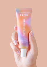 A hand holding a tube of FLWR Hand Cream - Fleur D'Oranger by The Aromatherapy Co.