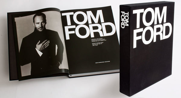 The Tom Ford book, showcasing iconic fashion brands like Gucci, is open on a white surface.