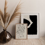 A PAPIER HQ | INK PRINT BLACK drawing on a table next to a vase of flowers. The drawing is available as Art Prints for delivery, with the option to purchase frames.