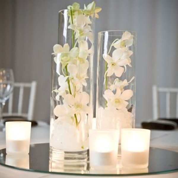 White orchids and candles adorning Glass Cylinder Vases - Various Sizes on a table.