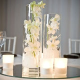 White orchids and candles adorning Glass Cylinder Vases - Various Sizes on a table.