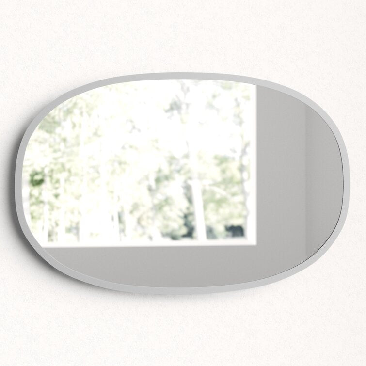 Umbra Hub oval mirror in black reflecting trees through a window
