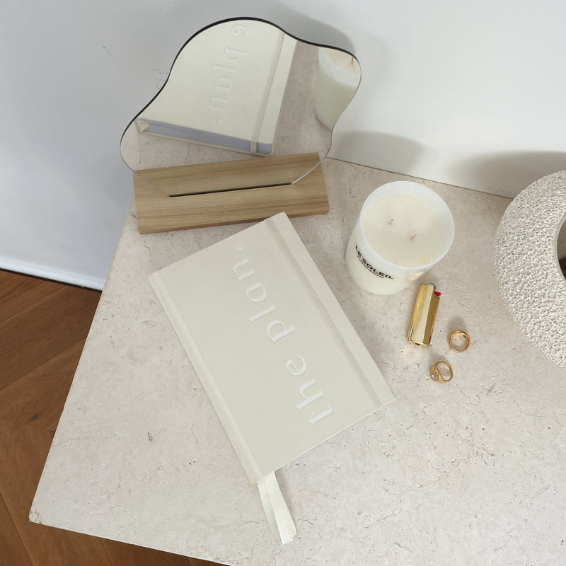 A limited edition Planner - Sand by Papier HQ on a table next to a mirror.