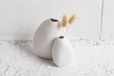 Two Harmie vases by Pipi in white ceramic sitting on a white wall.