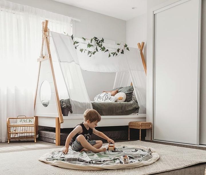A child's bedroom with a Wow Town Track Interactive play teepee bed and a cozy rug from Play Pouch.
