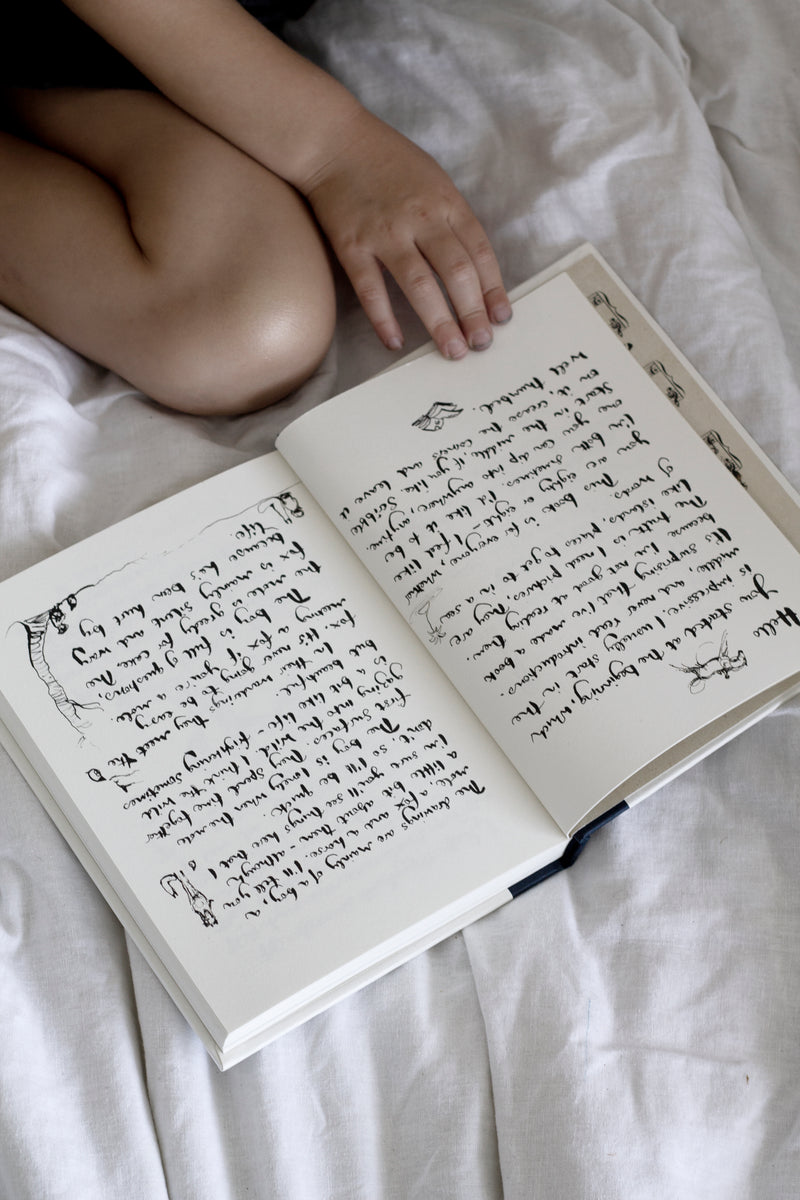 A child reading "Charlie Mackesy | The Boy, The Mole, The Fox and The Horse" book on a bed.