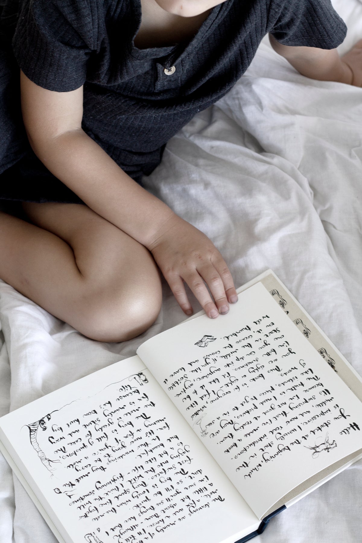 A young boy laying on a bed reading "Charlie Mackesy | The Boy, The Mole, The Fox and The Horse" by Books.