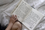 A child is reading "Charlie Mackesy | The Boy, The Mole, The Fox and The Horse" by Books on a bed.
