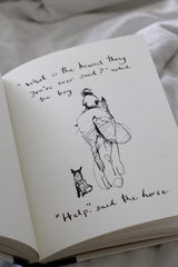 An open Charlie Mackesy | The Boy, The Mole, The Fox and The Horse book with a drawing of a cat on it.