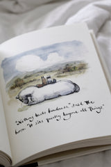 An open Charlie Mackesy book with a drawing of a sheep on it.
